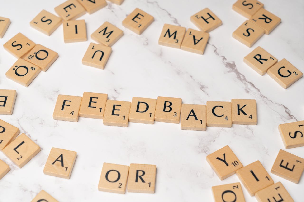 Wooden Scrabble tiles arranged to spell 'Feedback' on a marble background.
